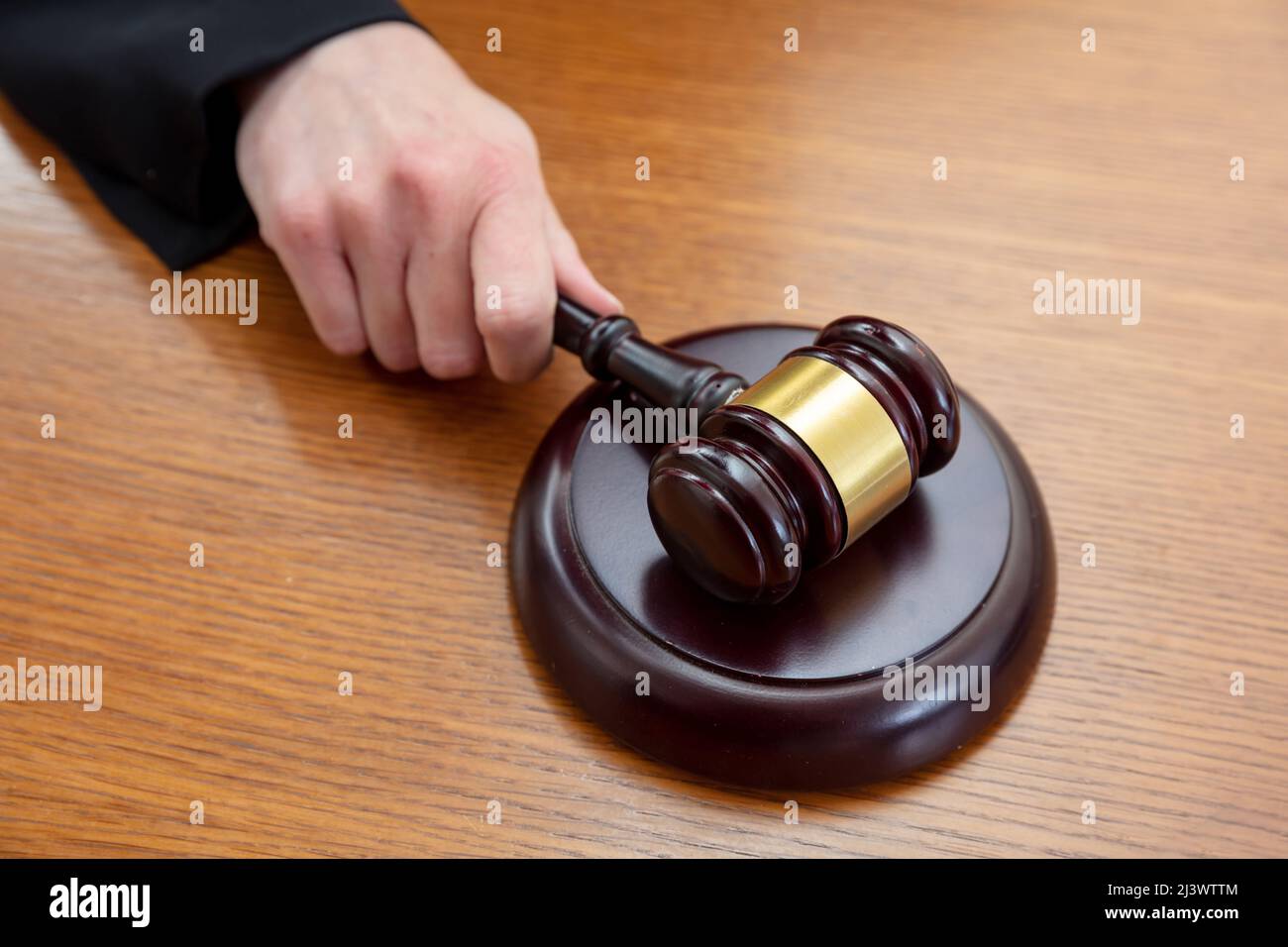 Judge female hand holding a gavel on wooden law court bench, close up above view. Justice and punishment concept Stock Photo