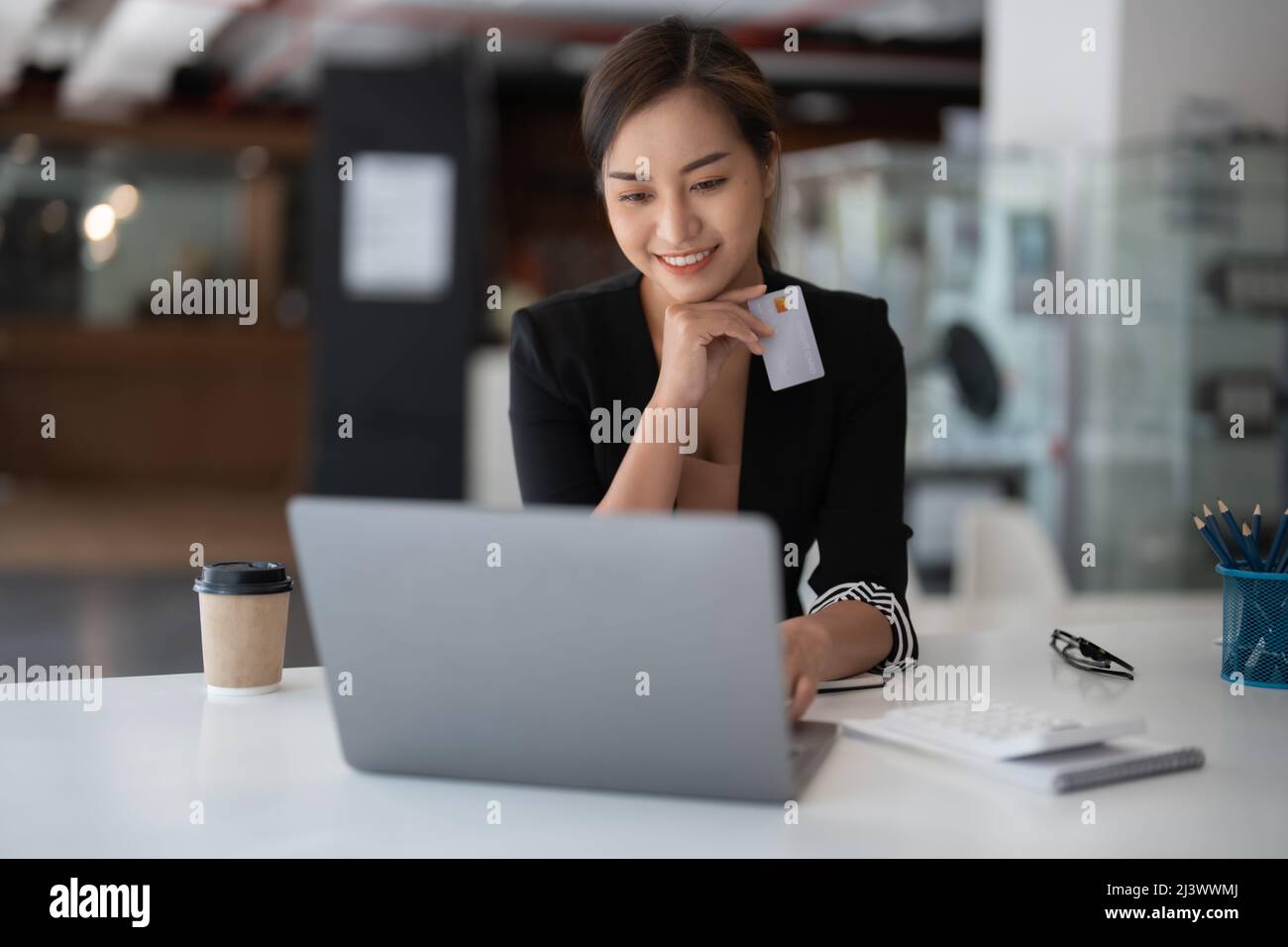 Asian girl making online payment using laptop and credit card for shopping at home Stock Photo