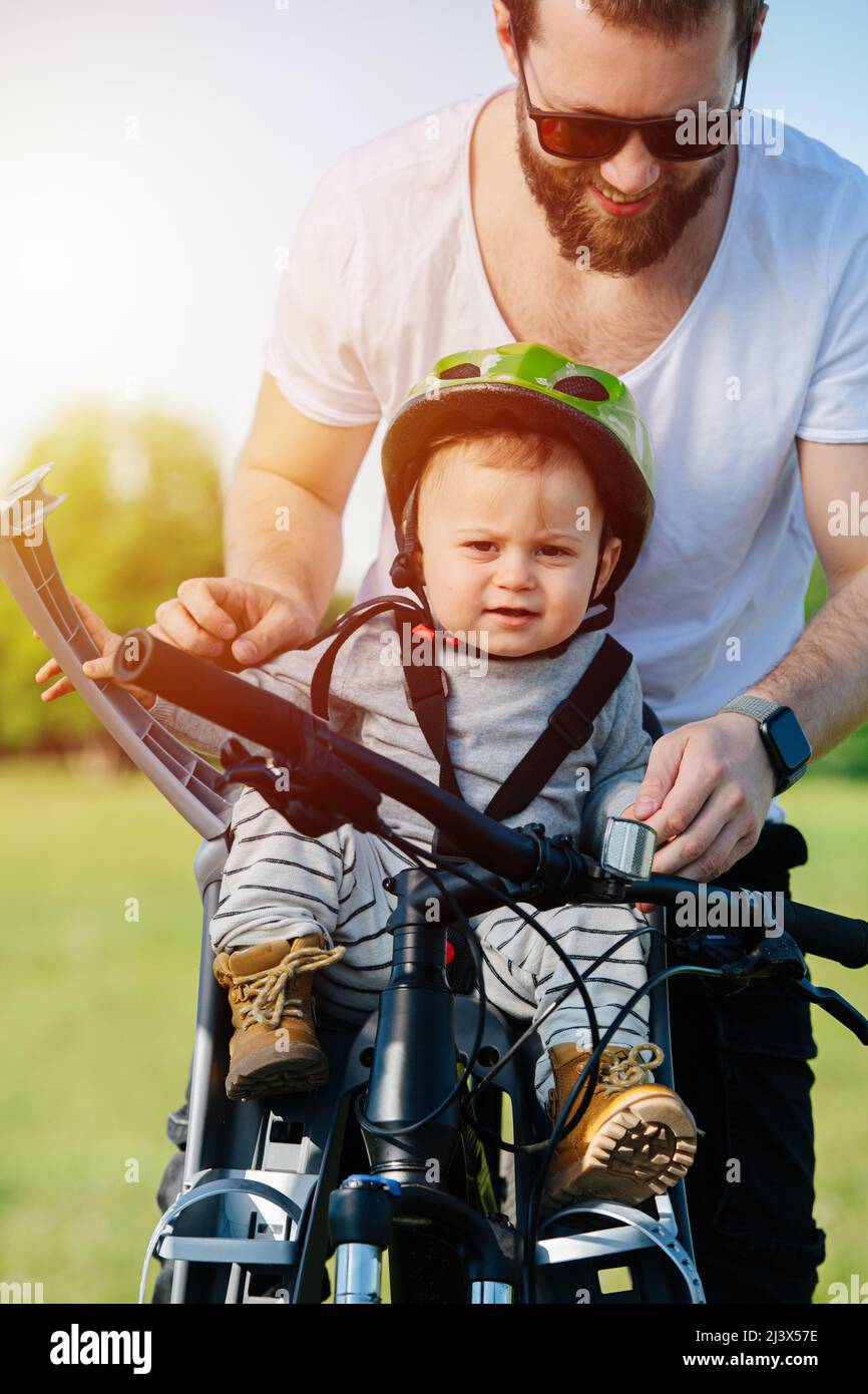 Amused father fitting his funny strict baby boy in a safety baby chair.  During bike travel on a beautiful spring sunny day Stock Photo - Alamy