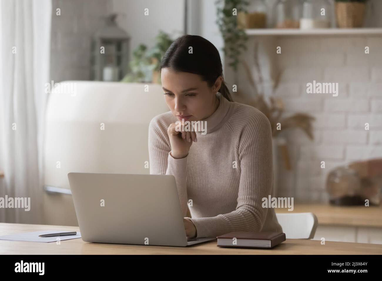 Thoughtful serious freelance worker woman working from home kitchen Stock Photo