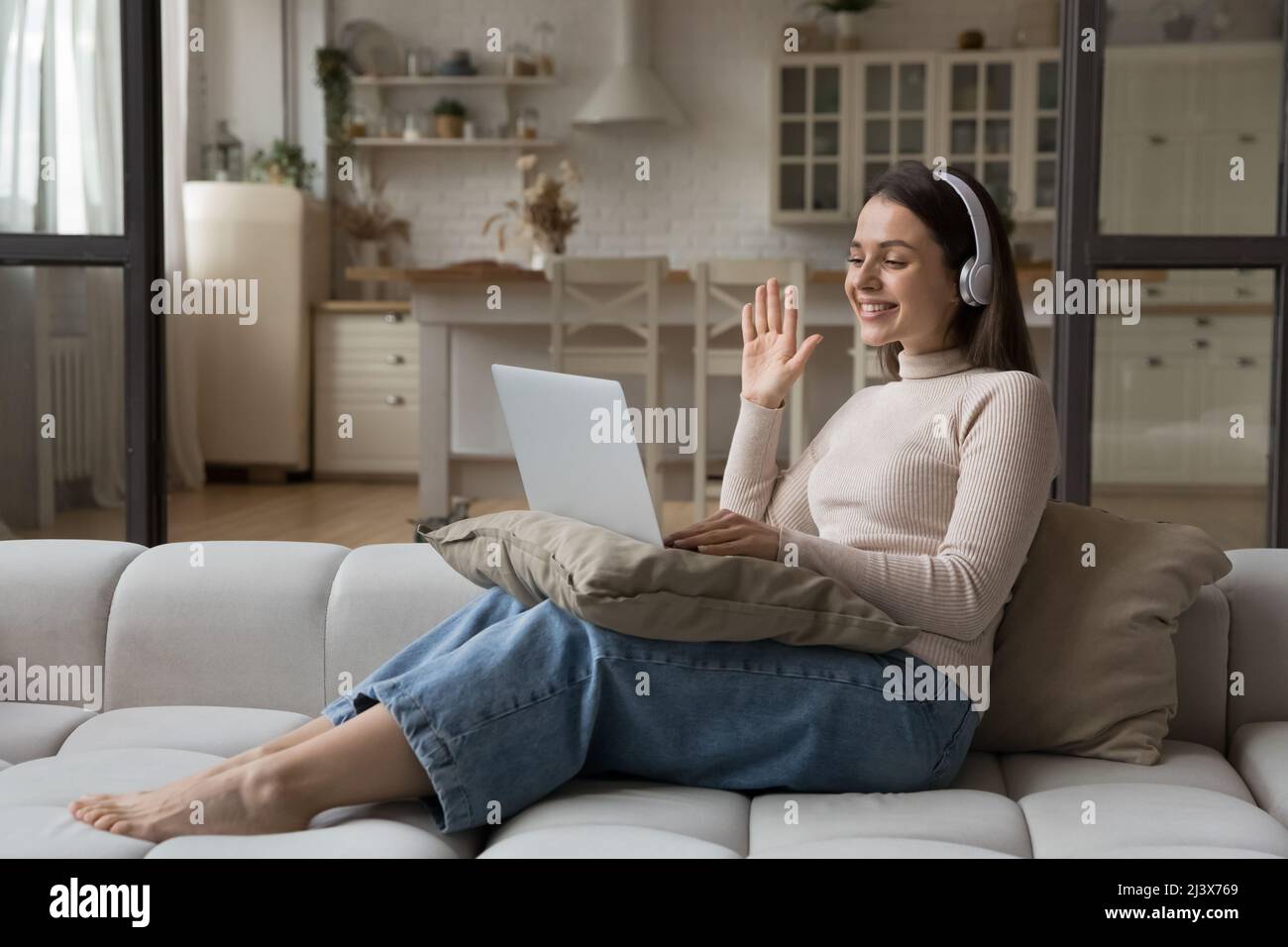 Friendly employee woman in wireless headphones talking on video call ...