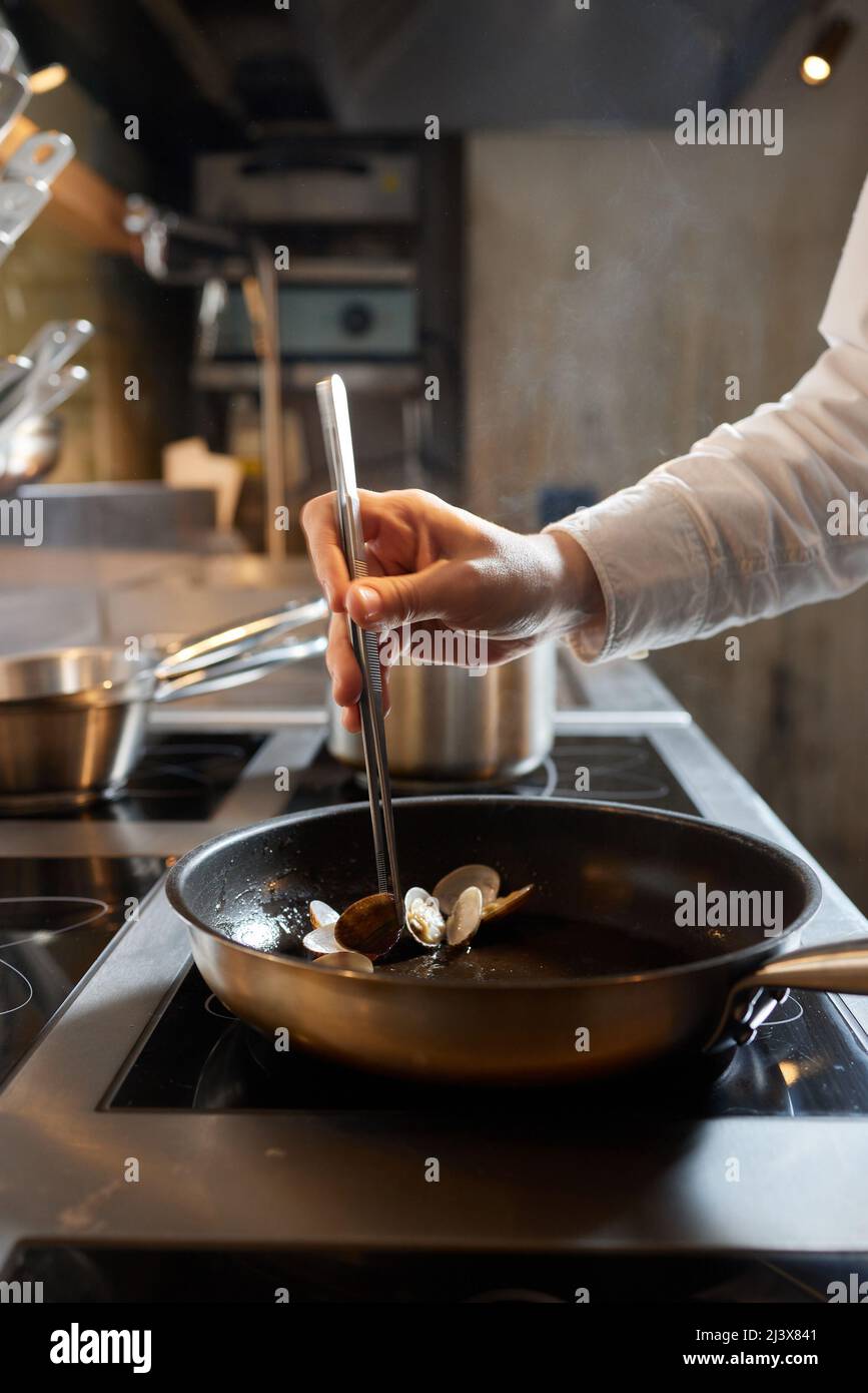 Chef frying mussels on commercial kitchen in restaurant, close-up on ...