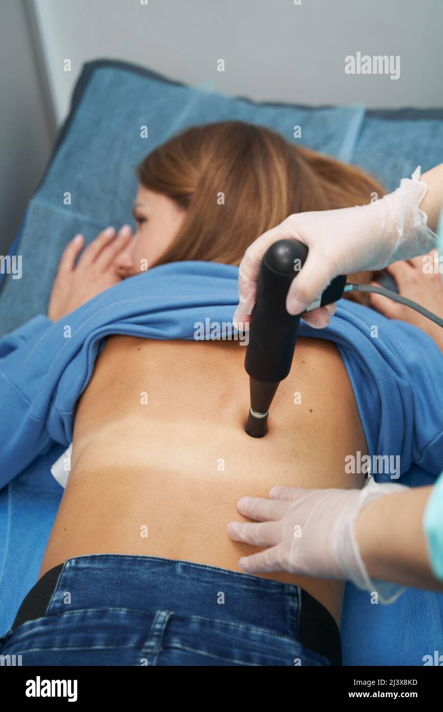 Woman receiving extracorporeal shockwave therapy in clinic Stock Photo