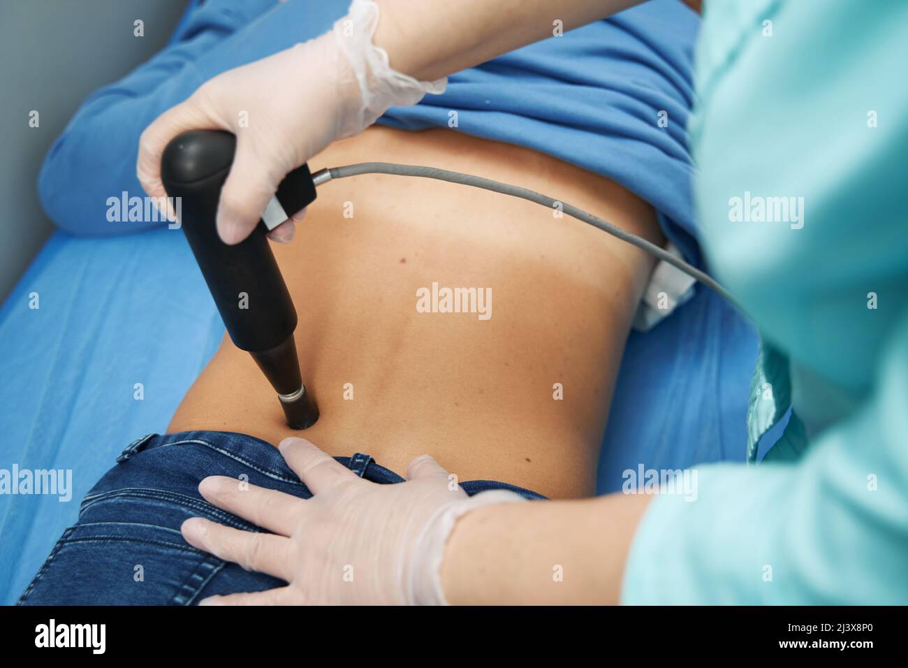 Female patient receiving extracorporeal shockwave therapy in clinic Stock Photo