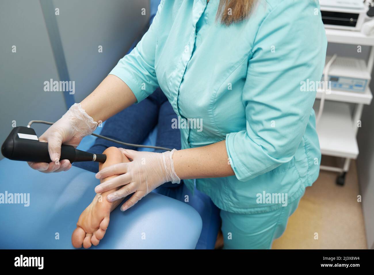 Doctor performing shockwave therapy procedure in clinic Stock Photo