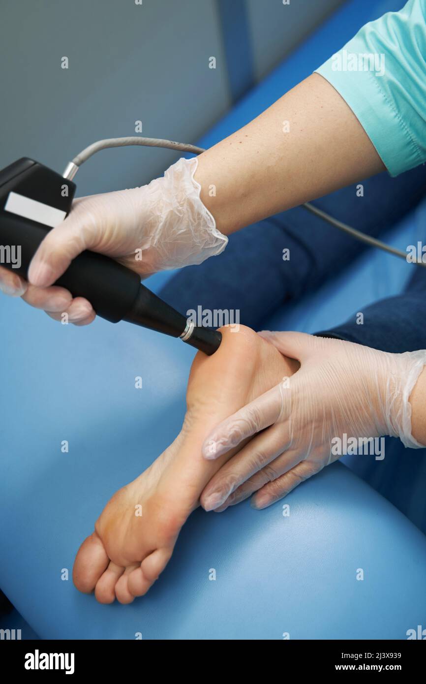 Female patient receiving shockwave therapy treatment in clinic Stock Photo