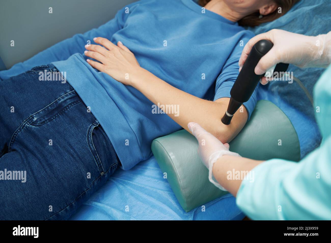 Doctor performing shockwave therapy procedure with pain relief device Stock Photo