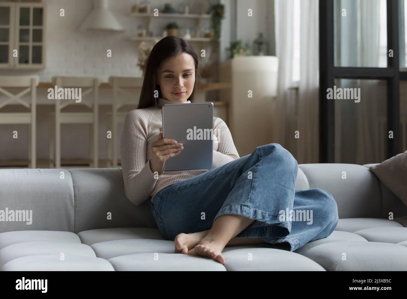 Positive focused millennial young woman using tablet computer Stock Photo