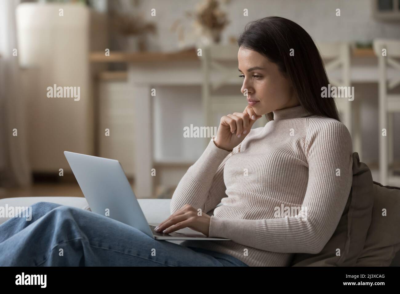 Relaxed Computer User Thoughtful serious young laptop user woman relaxing on couch Stock ...