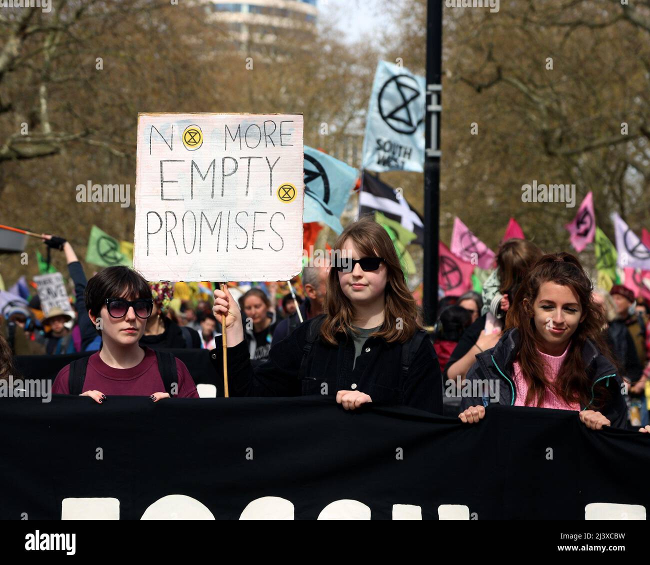 London, UK. 09th Apr, 2022. An Extinction Rebellion protester holds a sign that reads 'no more empty promises' as they march through London on day 2 of the climate activism week, planned by XR. 10th April 2022. Anna Hatfield/ Pathos Credit: Pathos Images/Alamy Live News Stock Photo