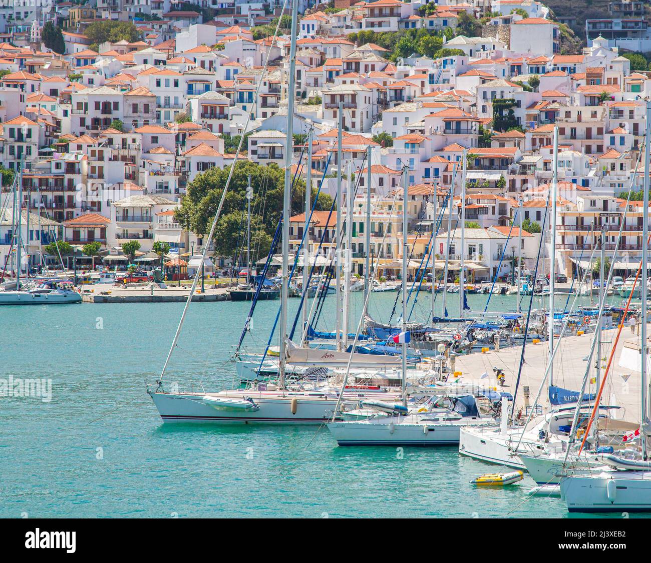 Boats moored on the harbour front and busy port of Skiathos in the Sporades Islands of Greece Stock Photo