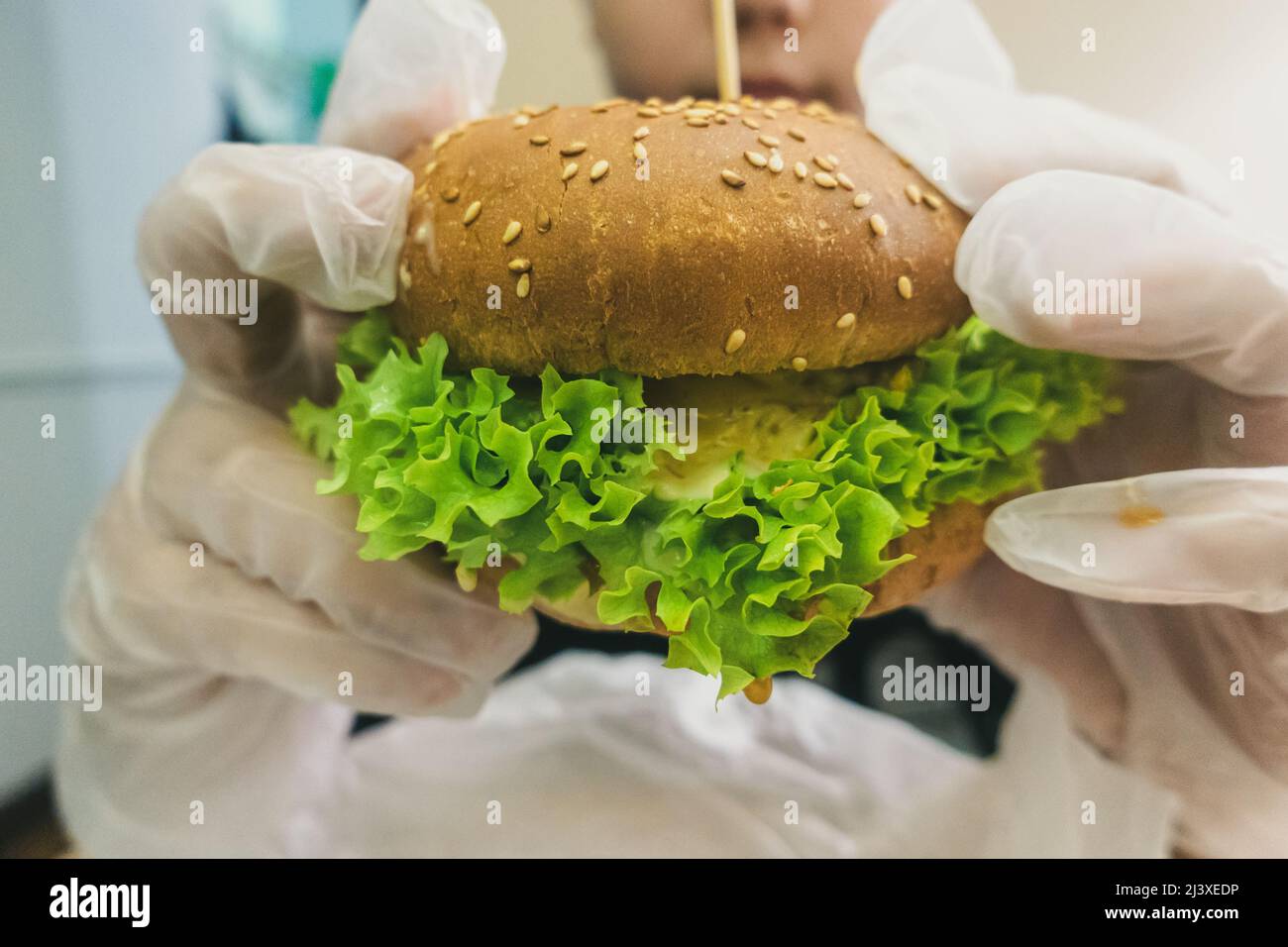 Man in rubber gloves holding a burger. Stock Photo