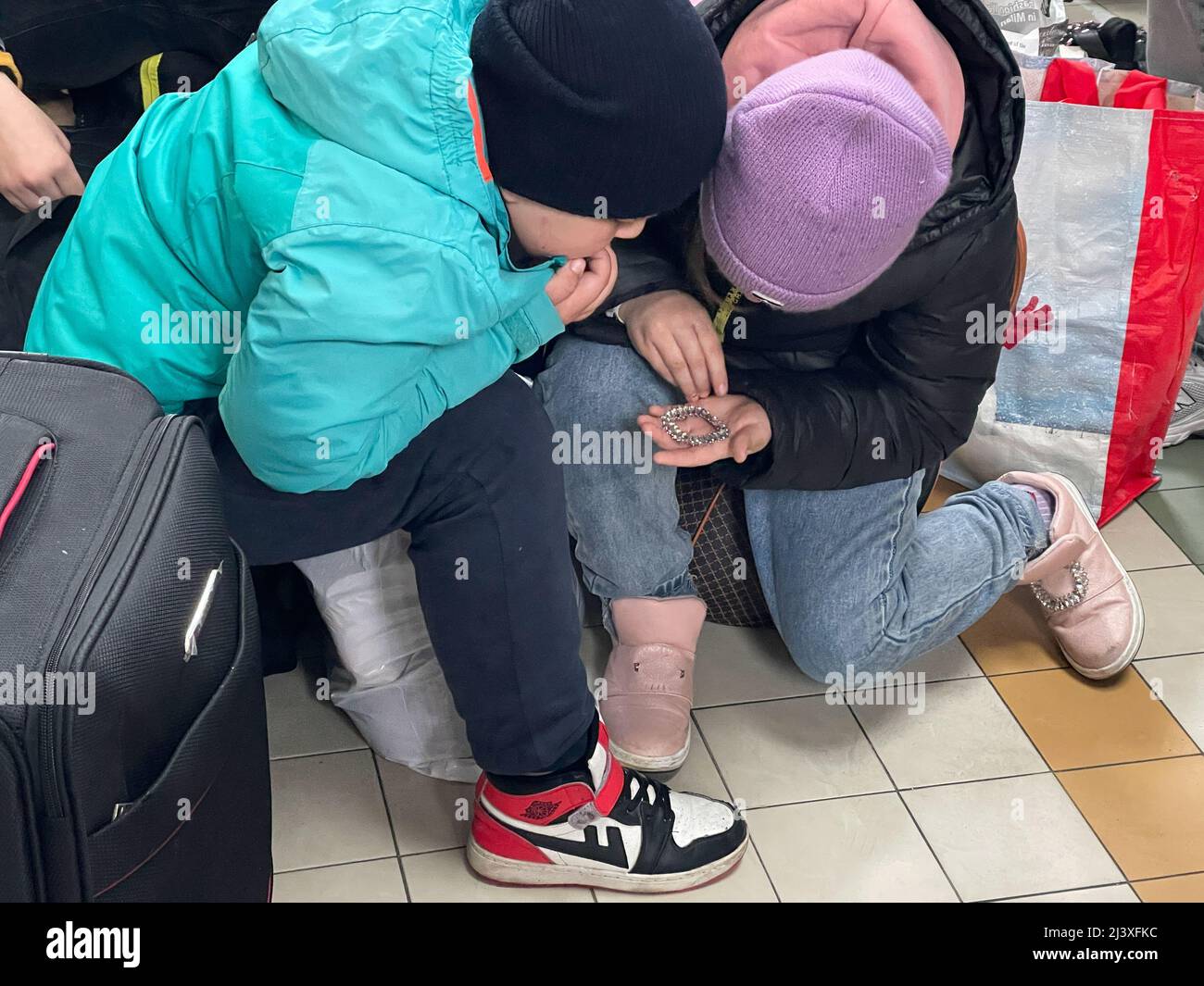 Przemysl, Poland. 9th Apr, 2022. Kids looking at a found treasure on a very cold and rainy day. Ukrainian refugees at Przemysl train station, the railway entry point into Poland closest to the border ''” the Ukrainian city of Lviv is less than 100 KM away ''” is teeming with people fleeing Russia's war on them, trying to board trains to safer places. (Credit Image: © Amy Katz/ZUMA Press Wire) Stock Photo