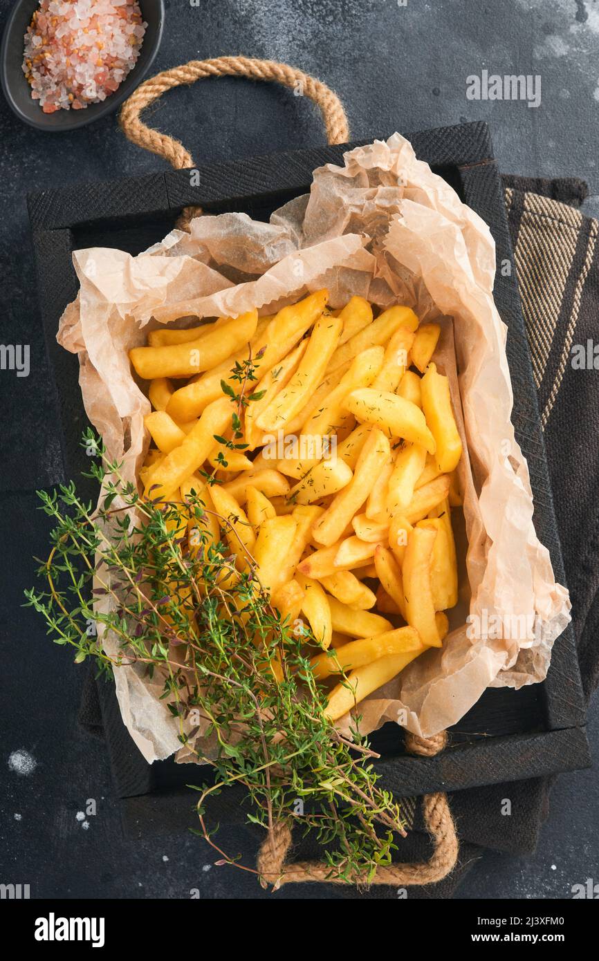 French fries. Tasty French fries server on parchment paper on wooden cutting board with tomato