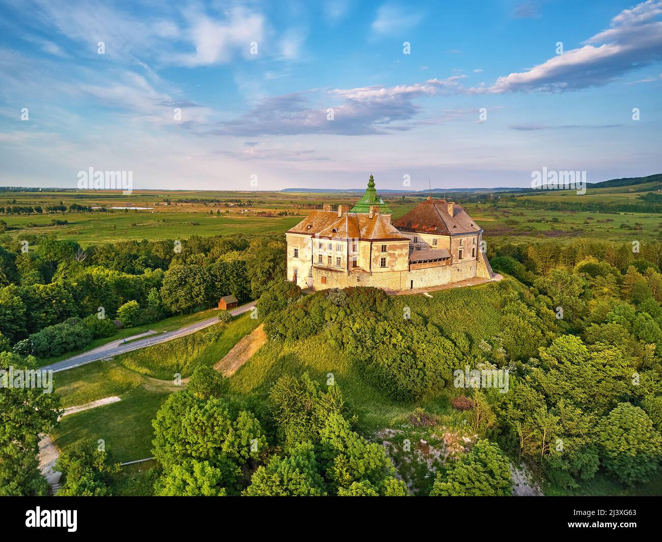 Medieval Olesko Palace aerial view. Picturesque sunny scene, green spring trees. Summer park on hills. Olesky Castle, Lviv region, Ukraine. Travel des Stock Photo
