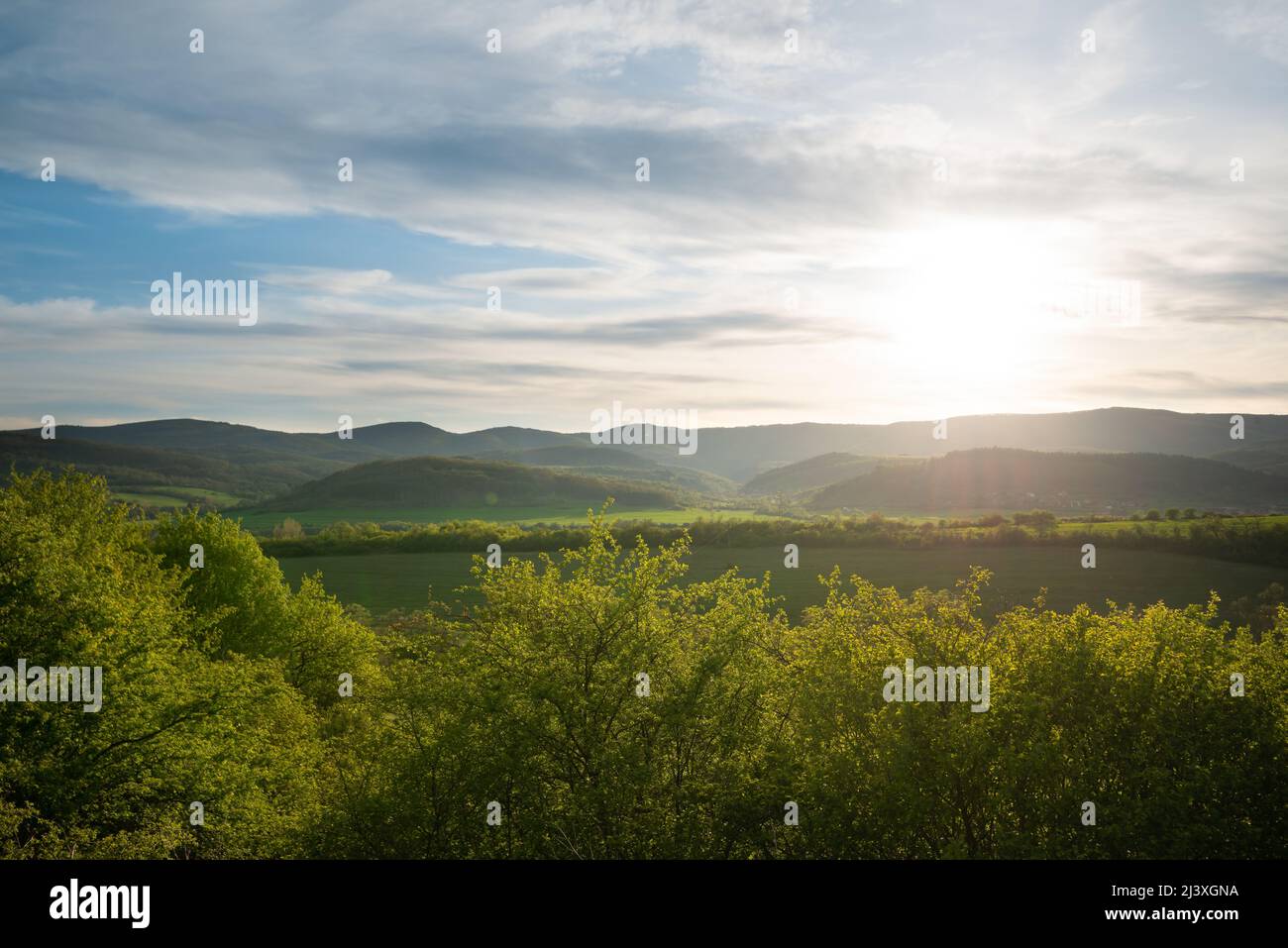 Beautiful green mountain landscape with sun and sun rays over the hills. Stock Photo