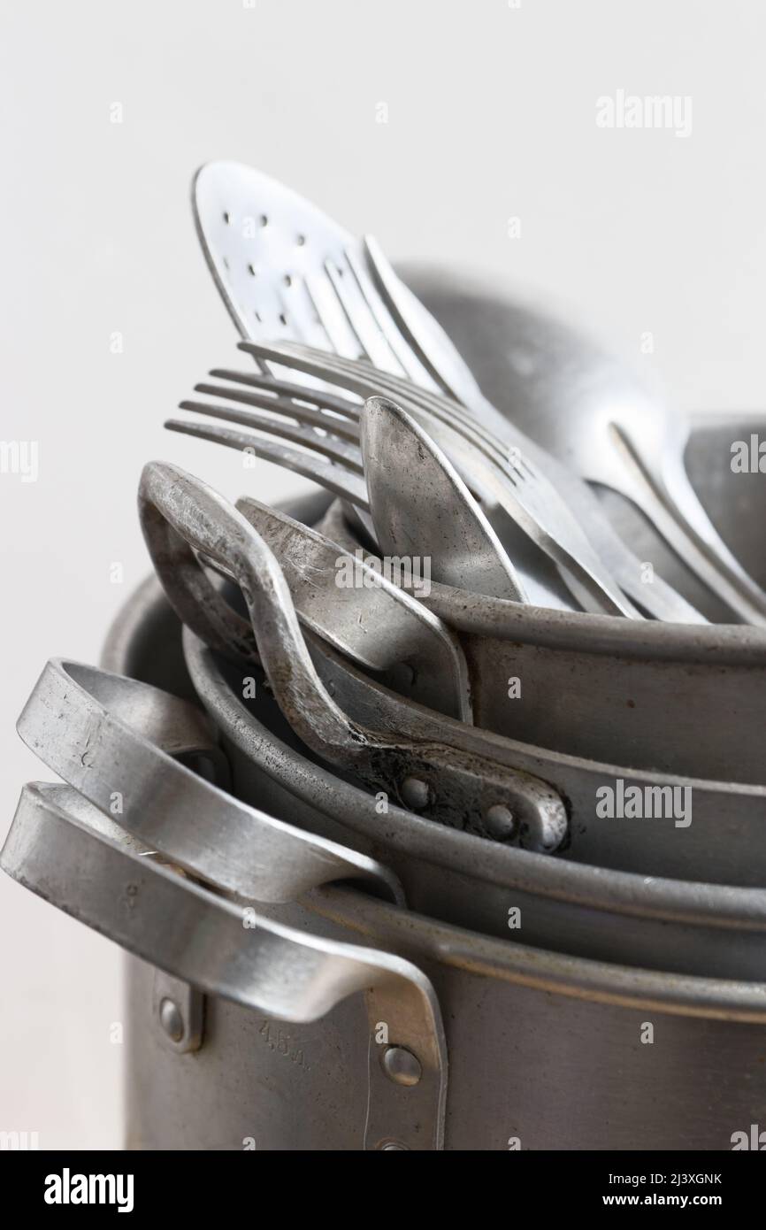 Vintage aluminum kitchen utensils, pan, metal cooking pots, spoons, forks on light background Stock Photo