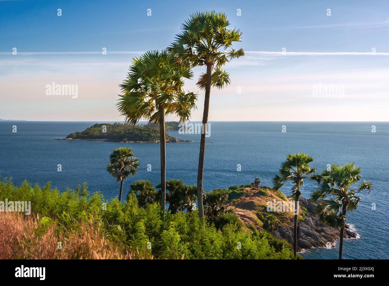 Beautiful tropical seascape with island view through exotic palm trees on a clear sunny day. Stock Photo