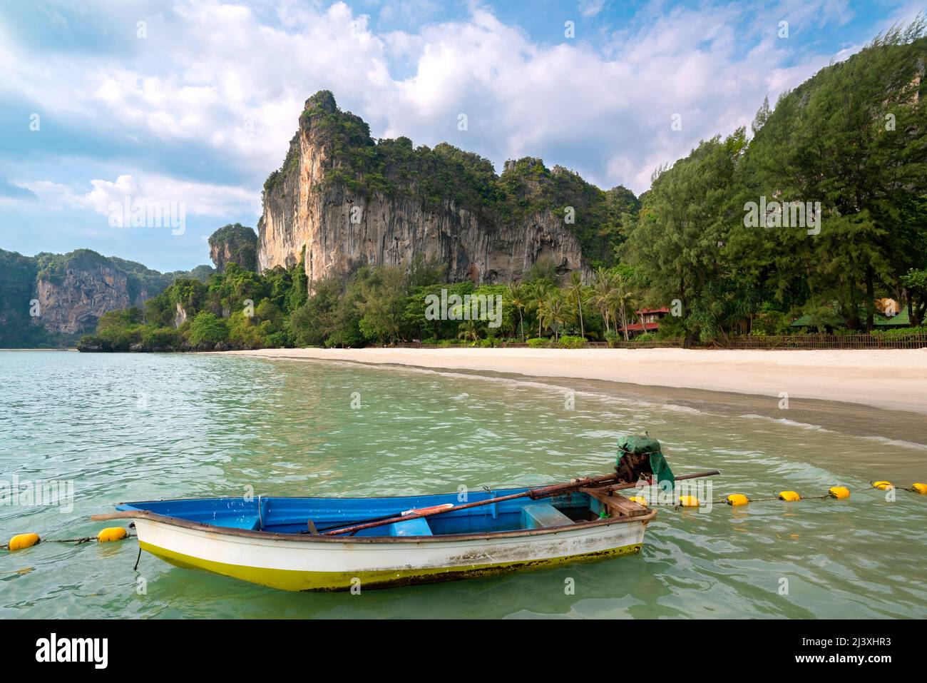 Empty exotic beach, high cliffs and fishing boat in the foreground. Railay Beach, Ao Nang, Krabi, Thailand Stock Photo