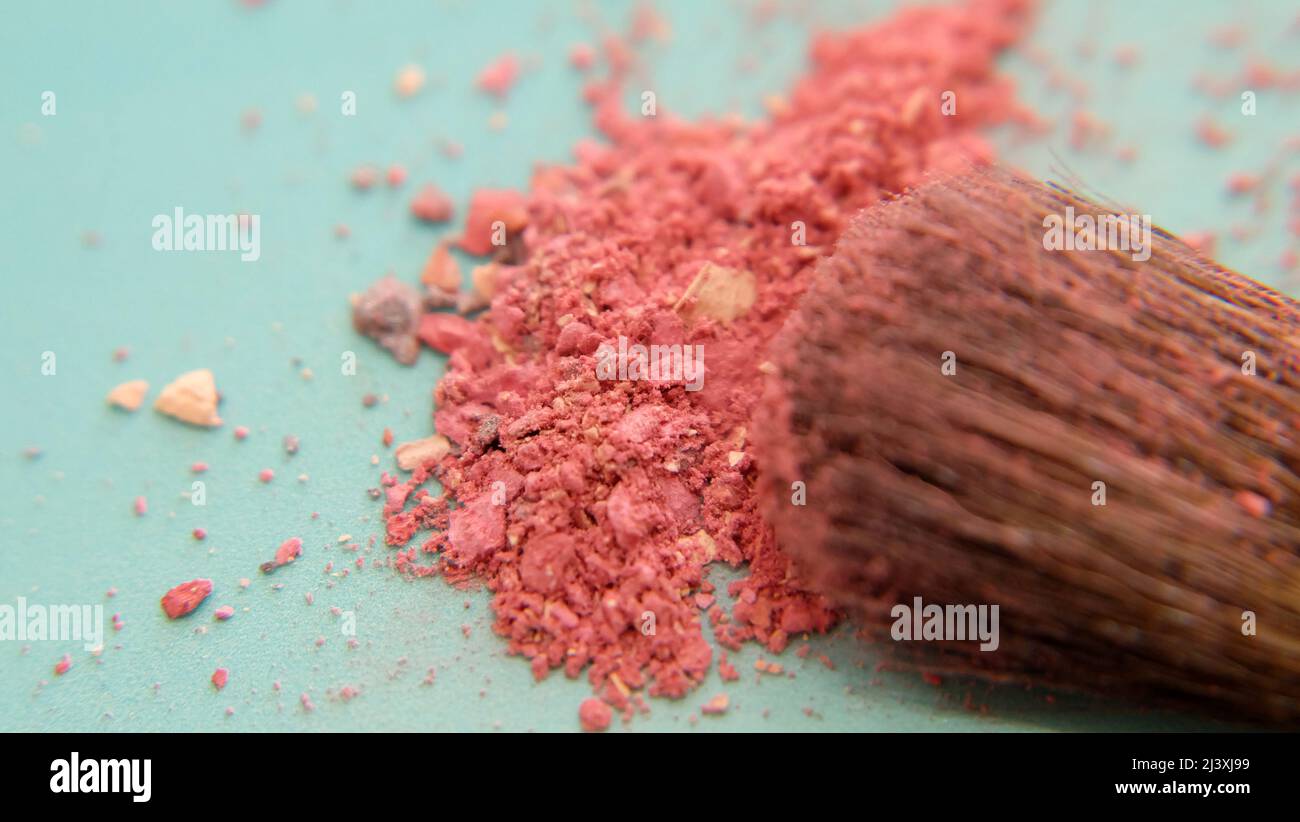 Closeup of the hair of brush head, covered with pink makeup powder, with a pile of pink cosmetic under the brush. Stock Photo