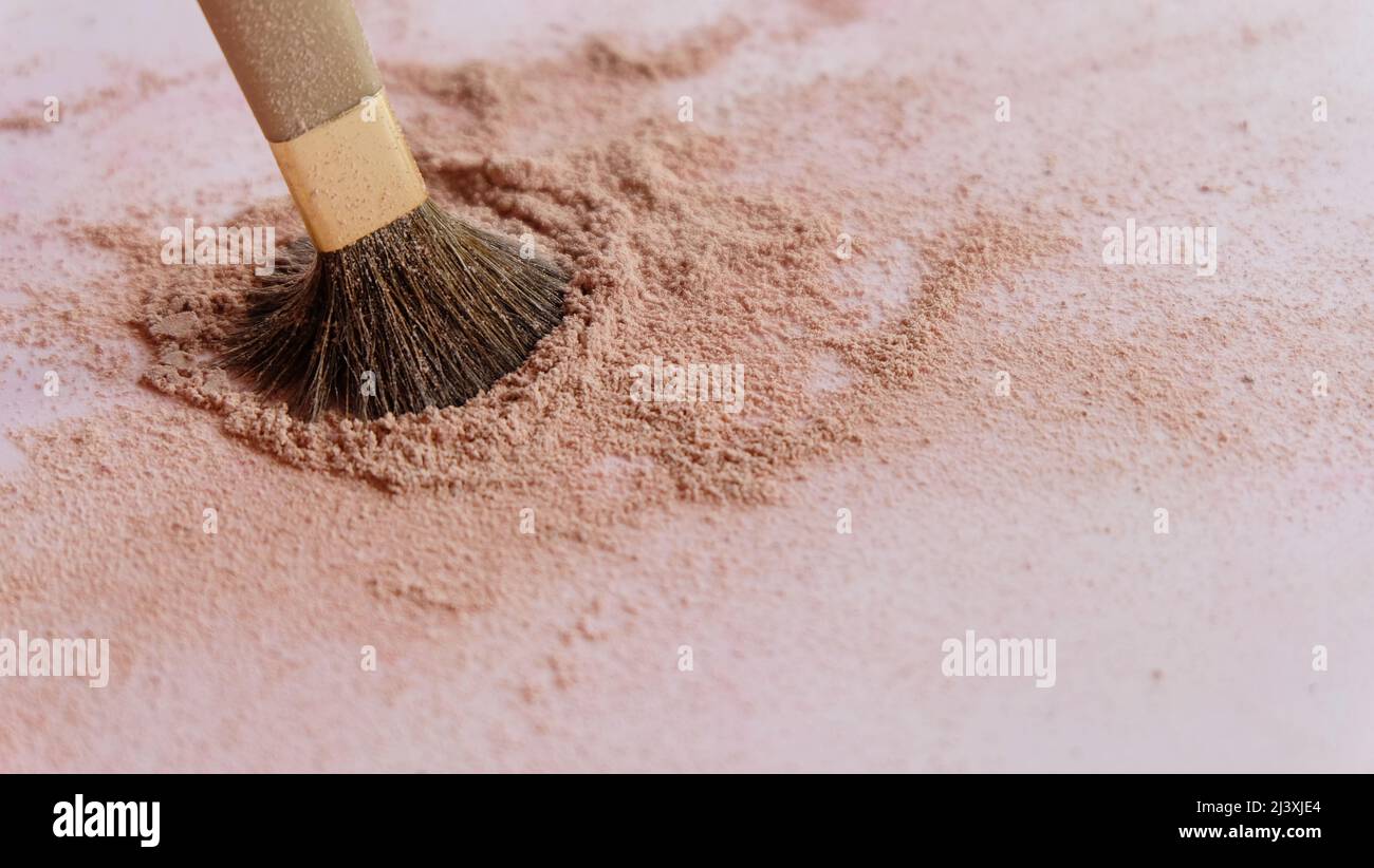 Closeup of a make-up brush, with the tip dipped into a pile of brown cosmetic foundation powder. Stock Photo