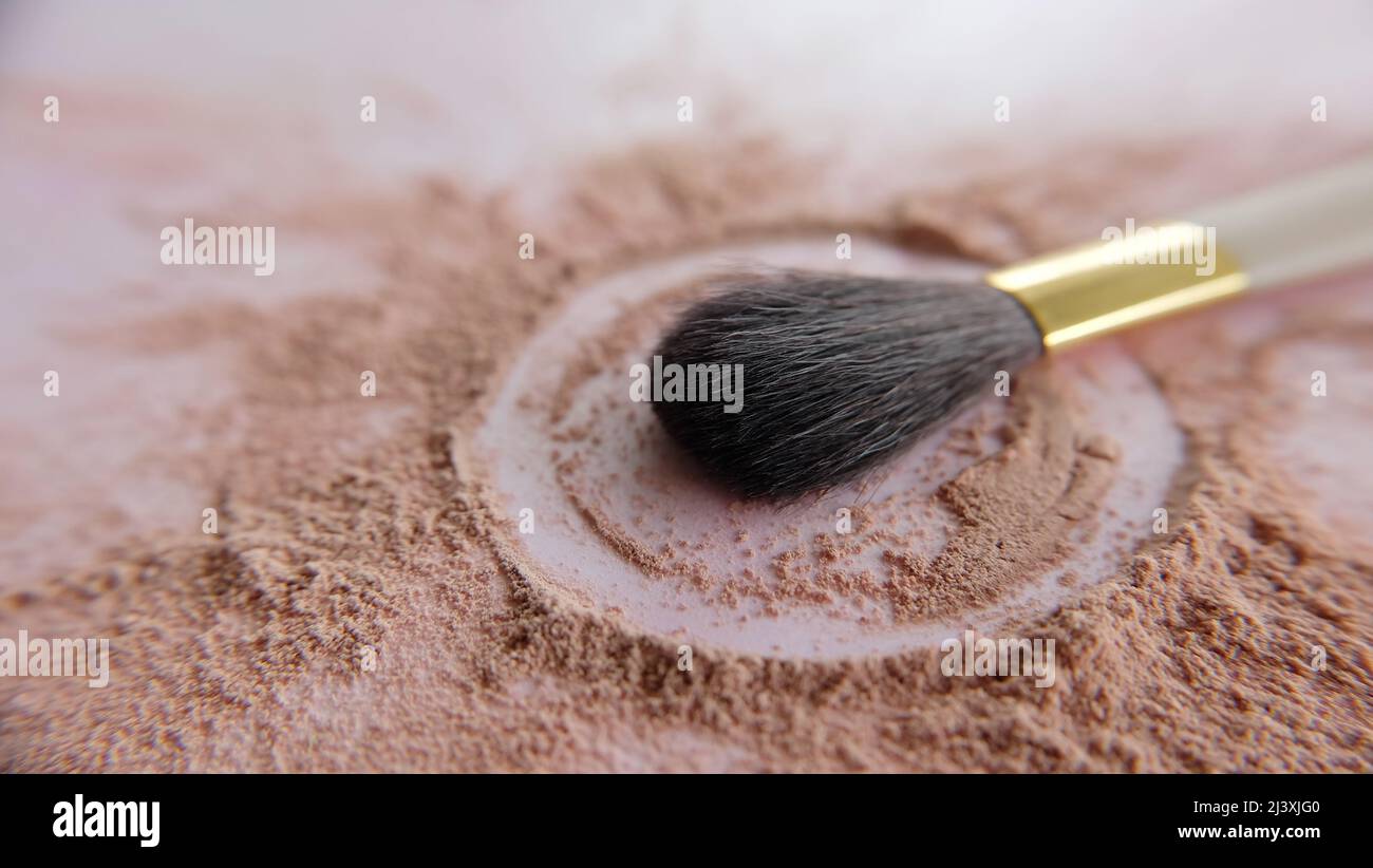 Closeup of a make-up brush, with brown cosmetic foundation powder scattered around the brush tip. Stock Photo