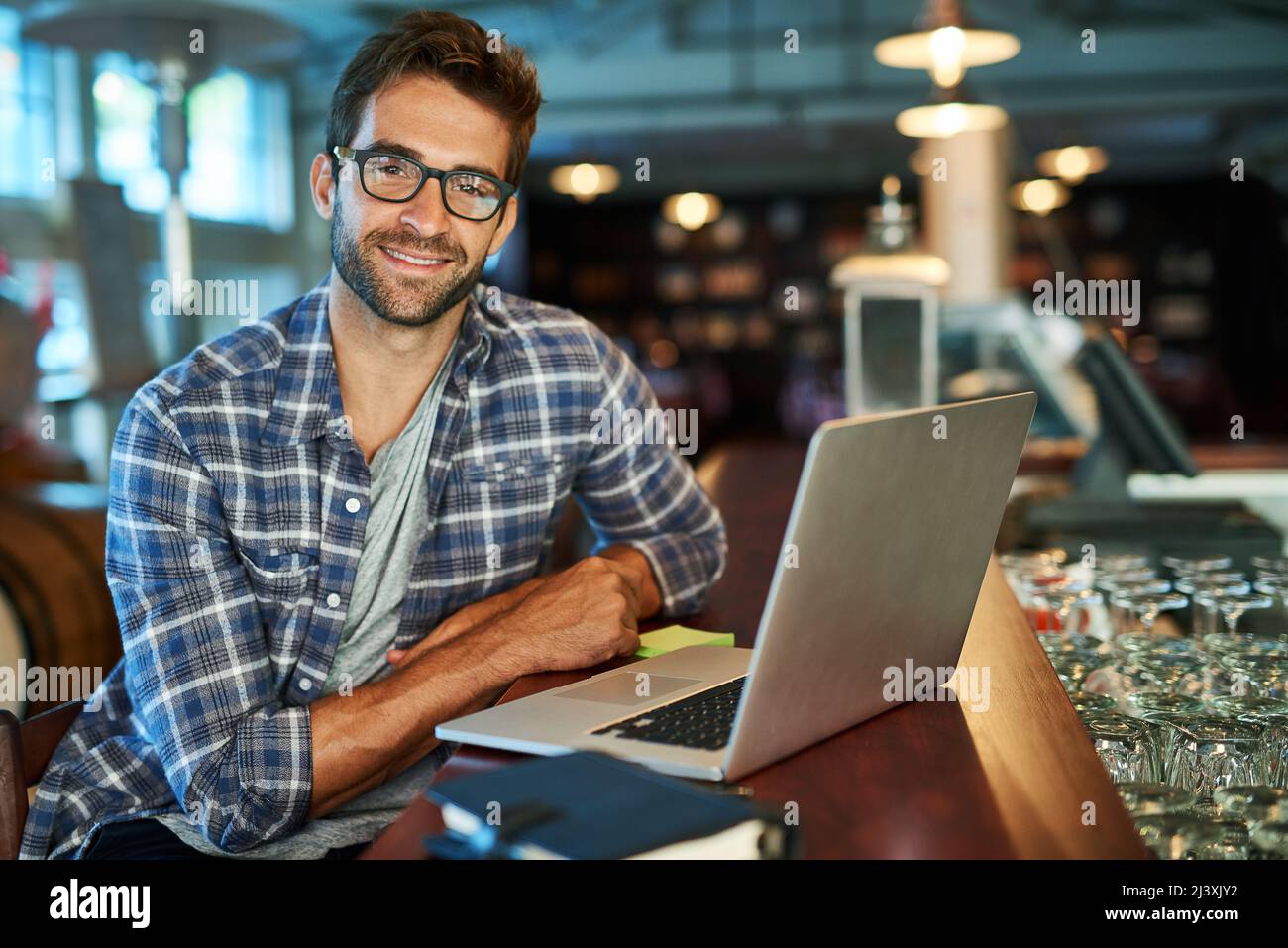 Loving free wifi. Portrait of a handsome young man sitting in a cafe using a laptop. Stock Photo