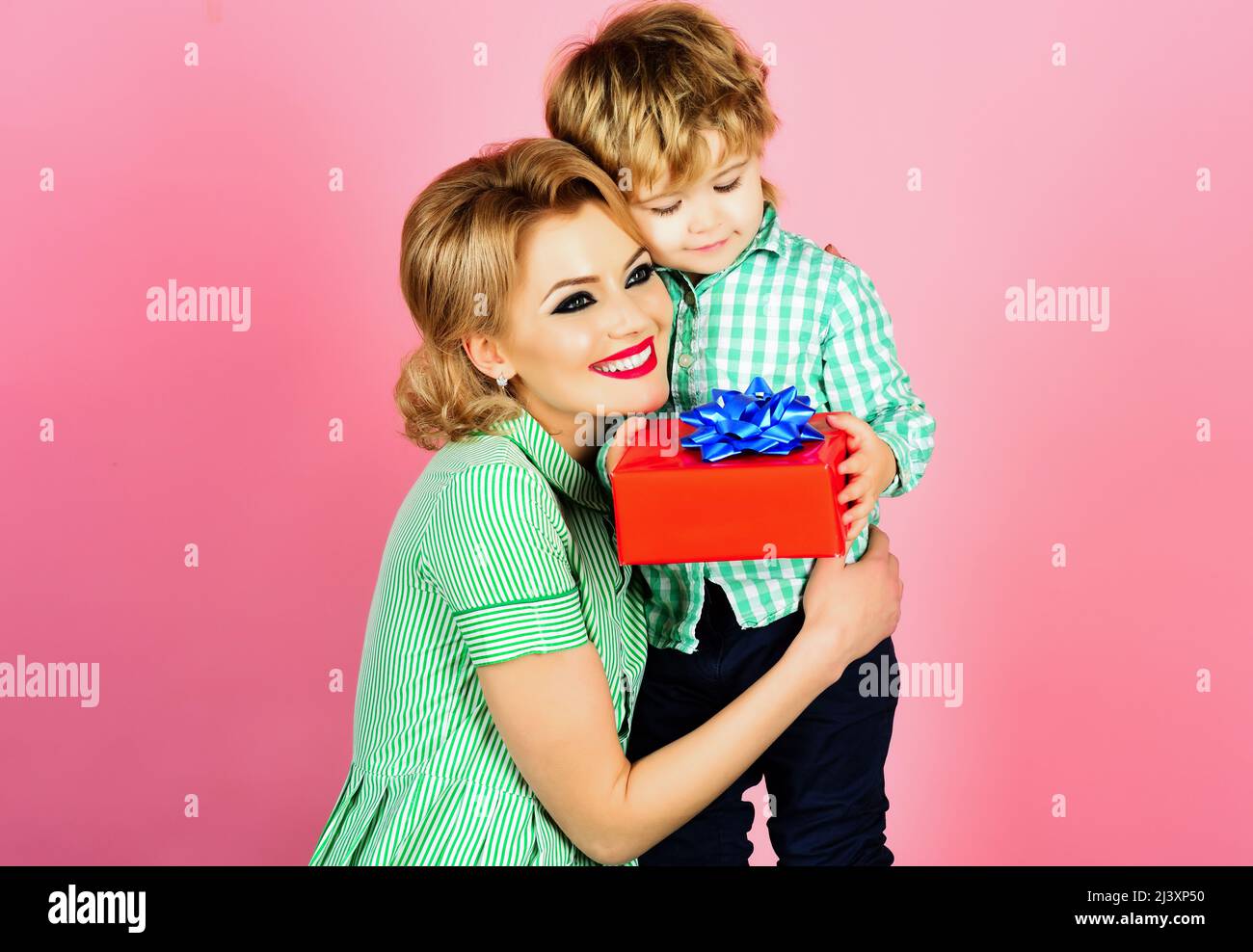 Family, mothers day, birthday celebration. Little son giving present his mother. Happy mom hugs son Stock Photo