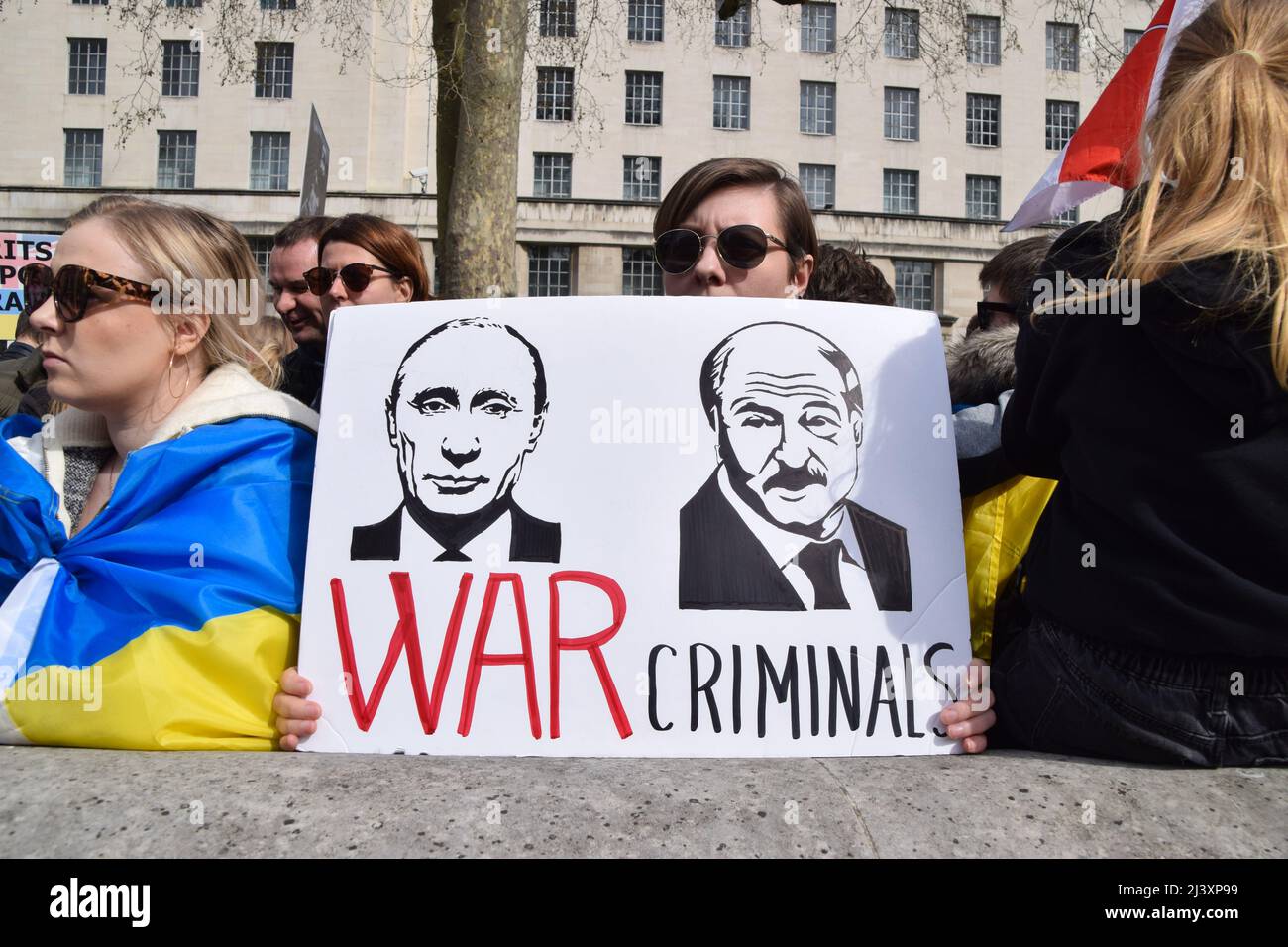 London, UK. 10th April 2022. A protester holds a sign calling Vladimir Putin and President of Belarus Alexander Lukashenko 'war criminals'. Demonstrators gathered outside Downing Street in solidarity with Ukraine, as reports emerge of massacres in Bucha and other towns and cities in Ukraine and atrocities reportedly committed by Russian troops. Credit: Vuk Valcic/Alamy Live News Stock Photo