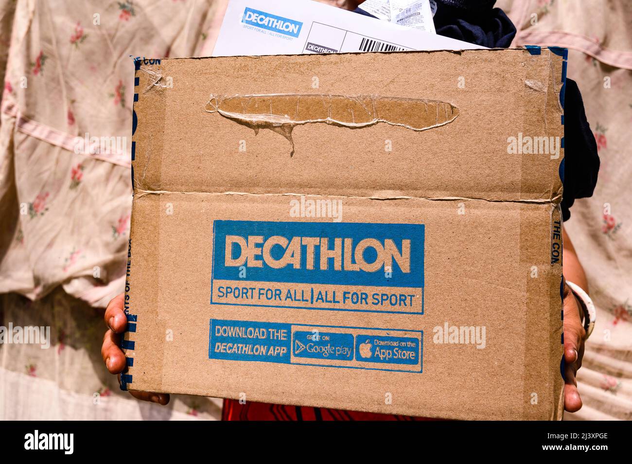 A woman is carrying a box of French sports equipment after checking orders  from the delivery person in Tehatta, West Bengal. Sportswear Company  Decathlon decided to suspend its operations in Russia after