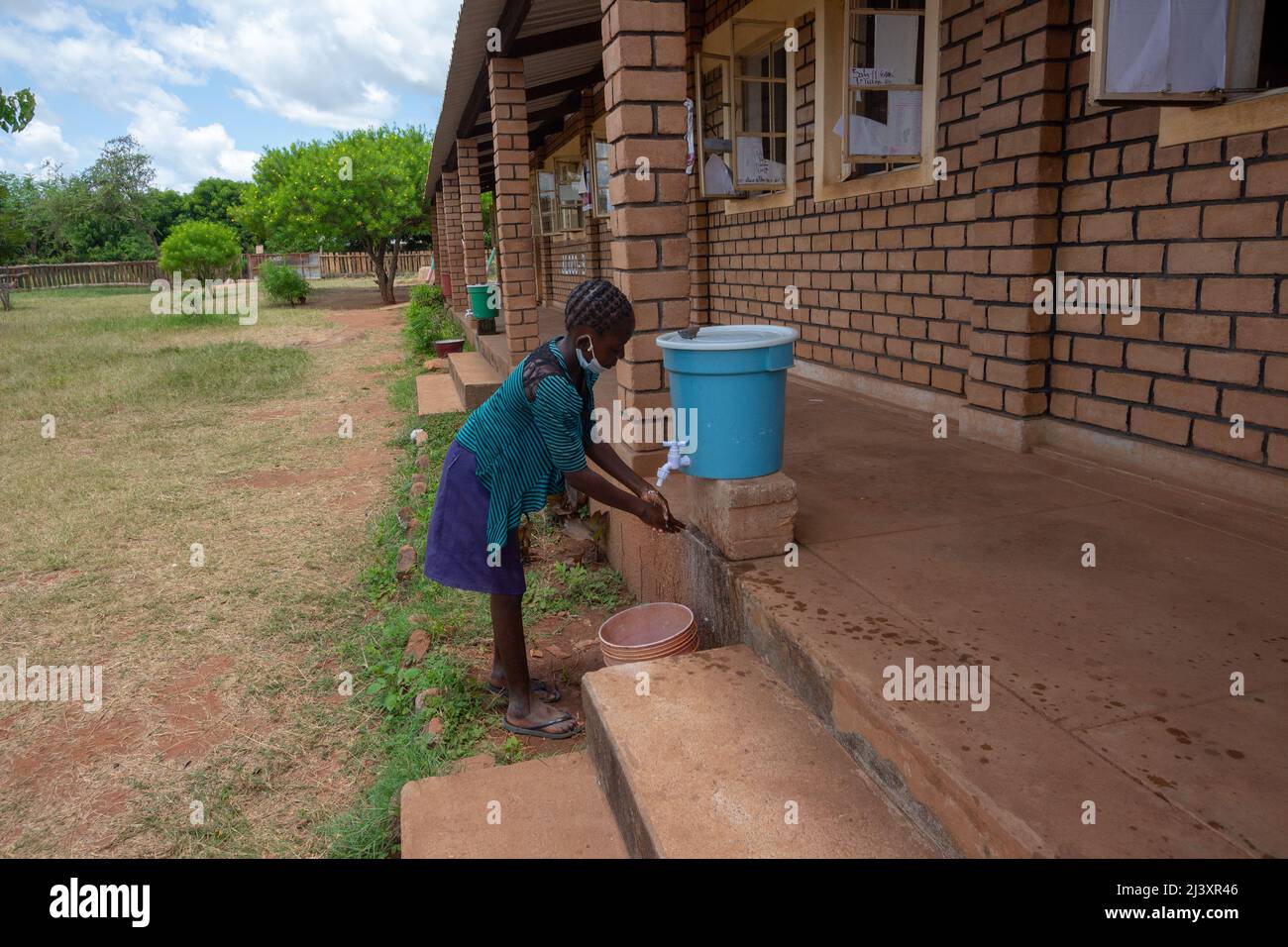 Little girl wearing facemask and washing hands before entering her classroom Stock Photo