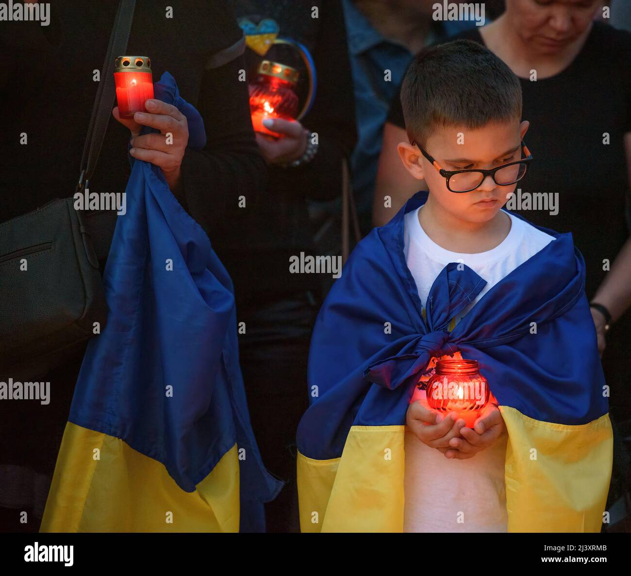 Limassol, Cyprus - April 5, 2022: Boy with a candle and flag of Ukraine during an event in memory of the Ukrainian victims killed in Bucha Stock Photo