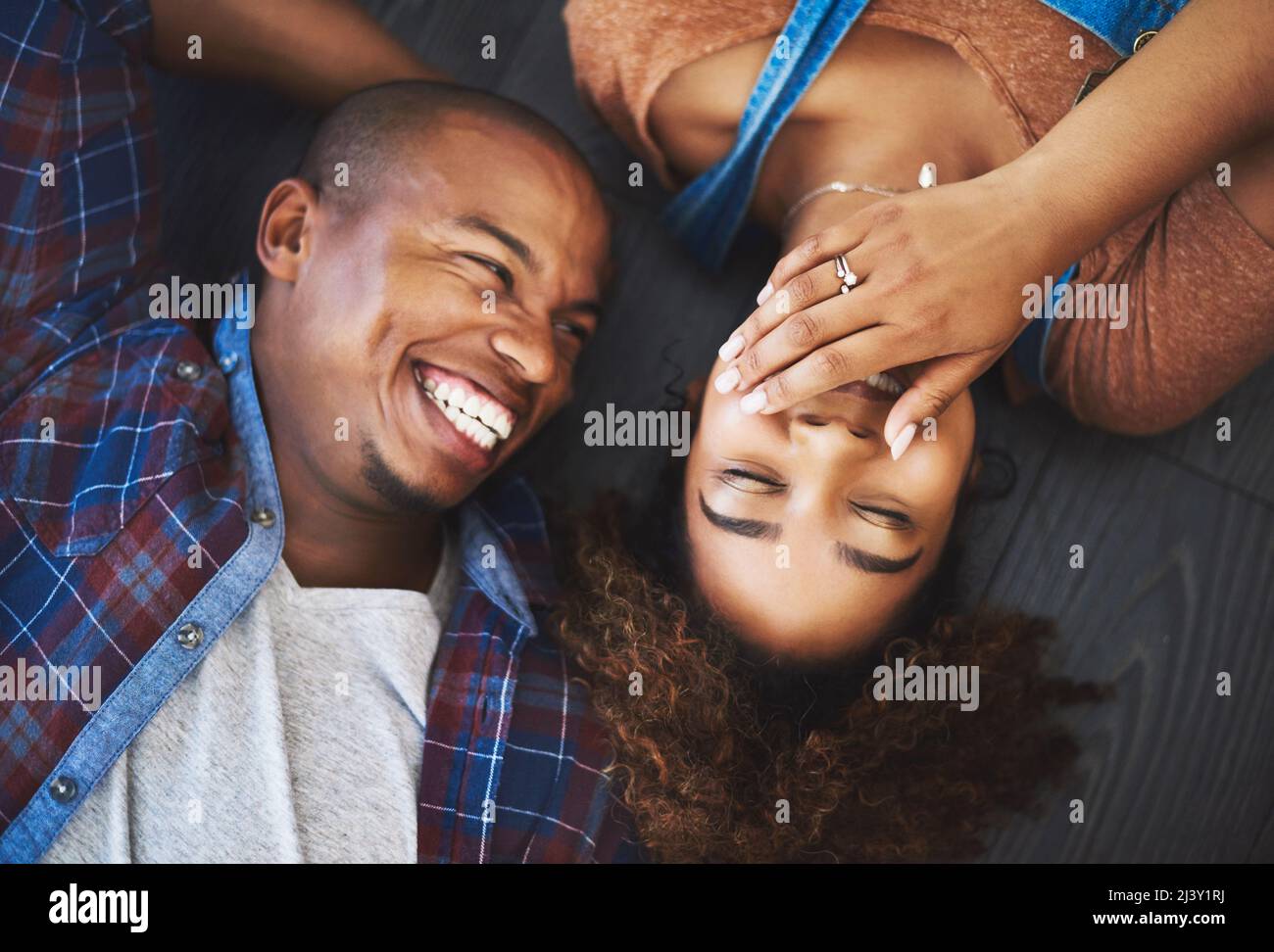 Looking forward to hearing her laugh everyday. High angle shot of an attractive young couple laying on the floor in their new home. Stock Photo