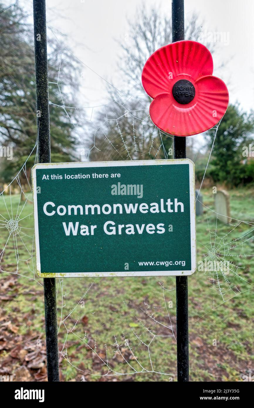 Warminster, Wiltshire,UK - January 18 2022: A Commonwealth War Graves sign and a Red Plastic Remembrance poppy on a churchyard gate at St Johns church Stock Photo