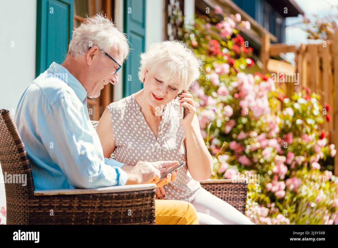 Senior couple looking at their phone in the garden Stock Photo