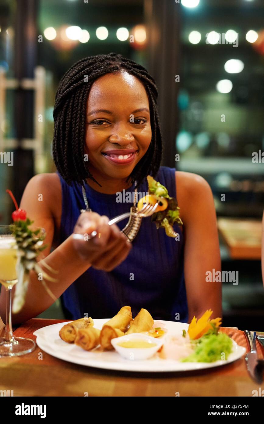 Its my favourite place to eat. Portrait of an attractive young woman eating a meal in a restaurant. Stock Photo
