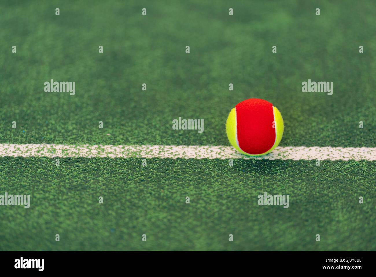 Red yellow tennis ball on tennis court. Horizontal education and sport