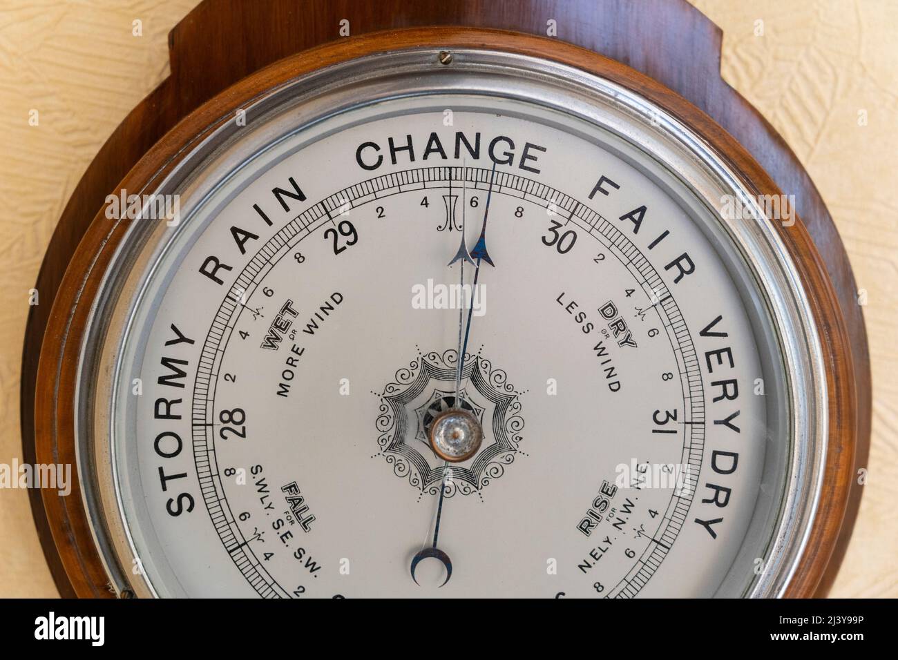 British made antique aneroid barometer with a face showing stormy, rain, change, fair and very dry, currently forecasting a change in the weather. UK Stock Photo