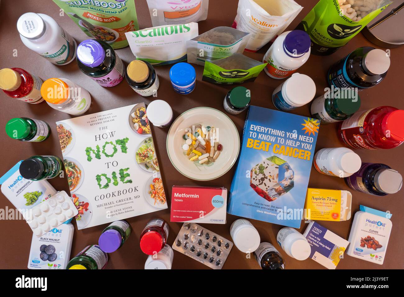 A selection of the many medicines, vitamin and food supplements taken by someone trying to recover from cancer, with books on surviving cancer. UK Stock Photo