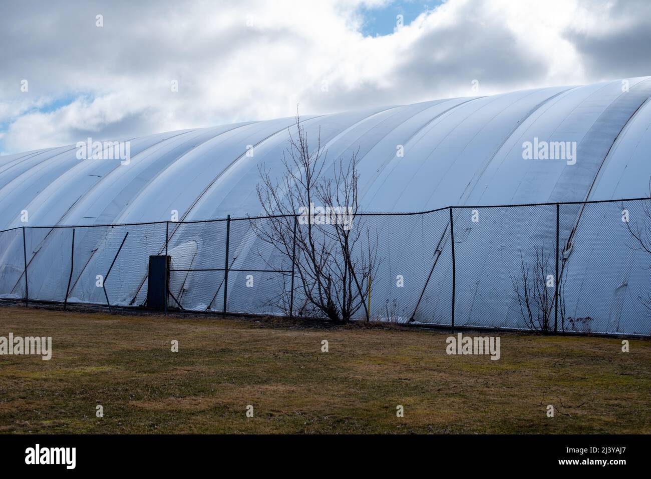 The exterior of a white semi permanent indoor tennis court dome tent. The polythene symmetrical pattern of the prefabricated pressurized air bubble Stock Photo