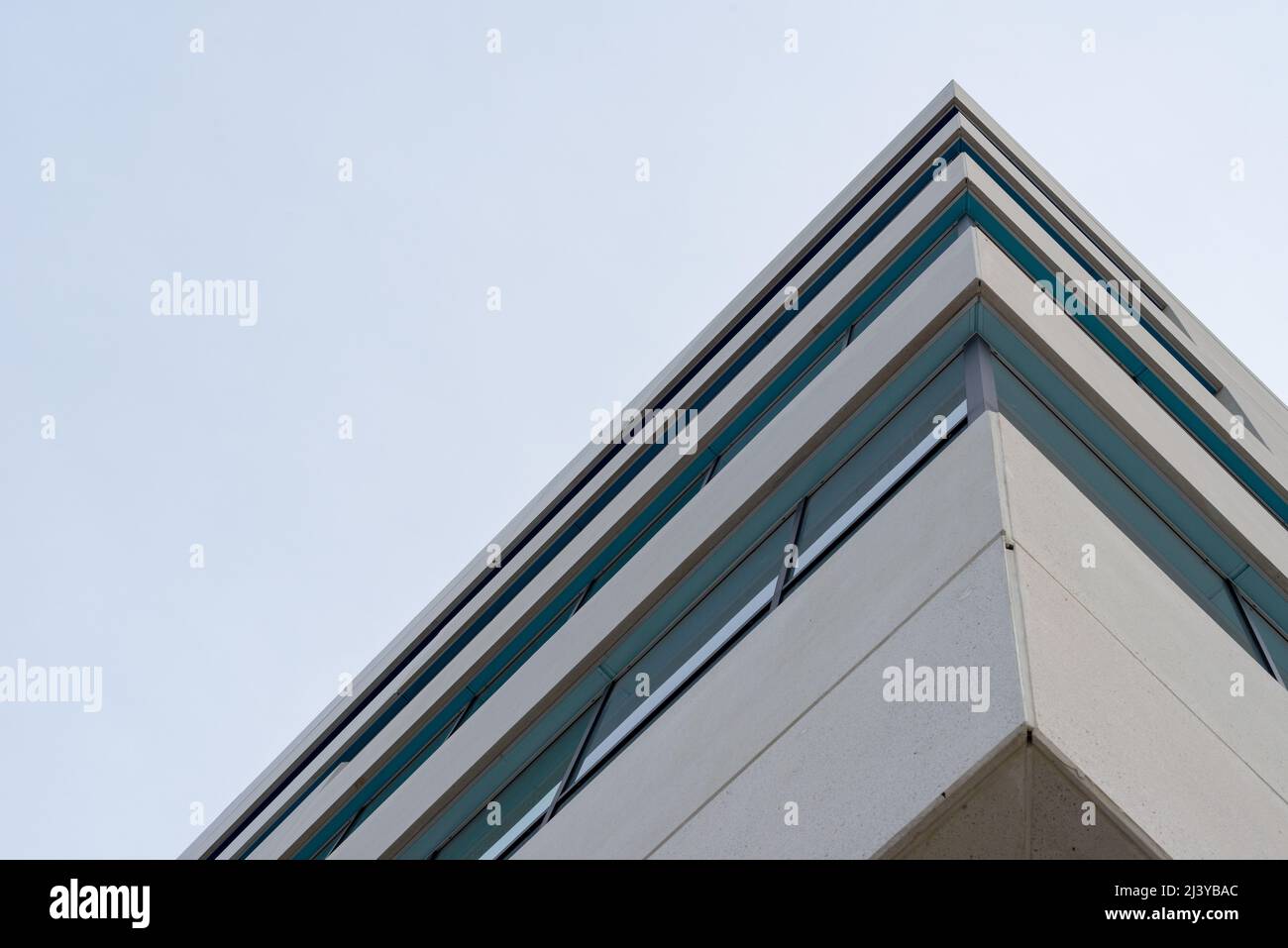 The exterior wall of a contemporary commercial style building with aluminum metal composite panels and glass windows. It's a futuristic building. Stock Photo