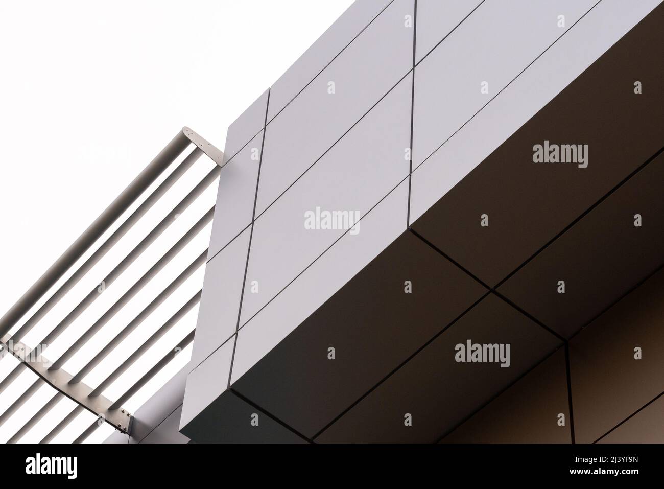 The exterior wall of a contemporary commercial style building with aluminum metal composite panels and glass windows. It's a futuristic building. Stock Photo