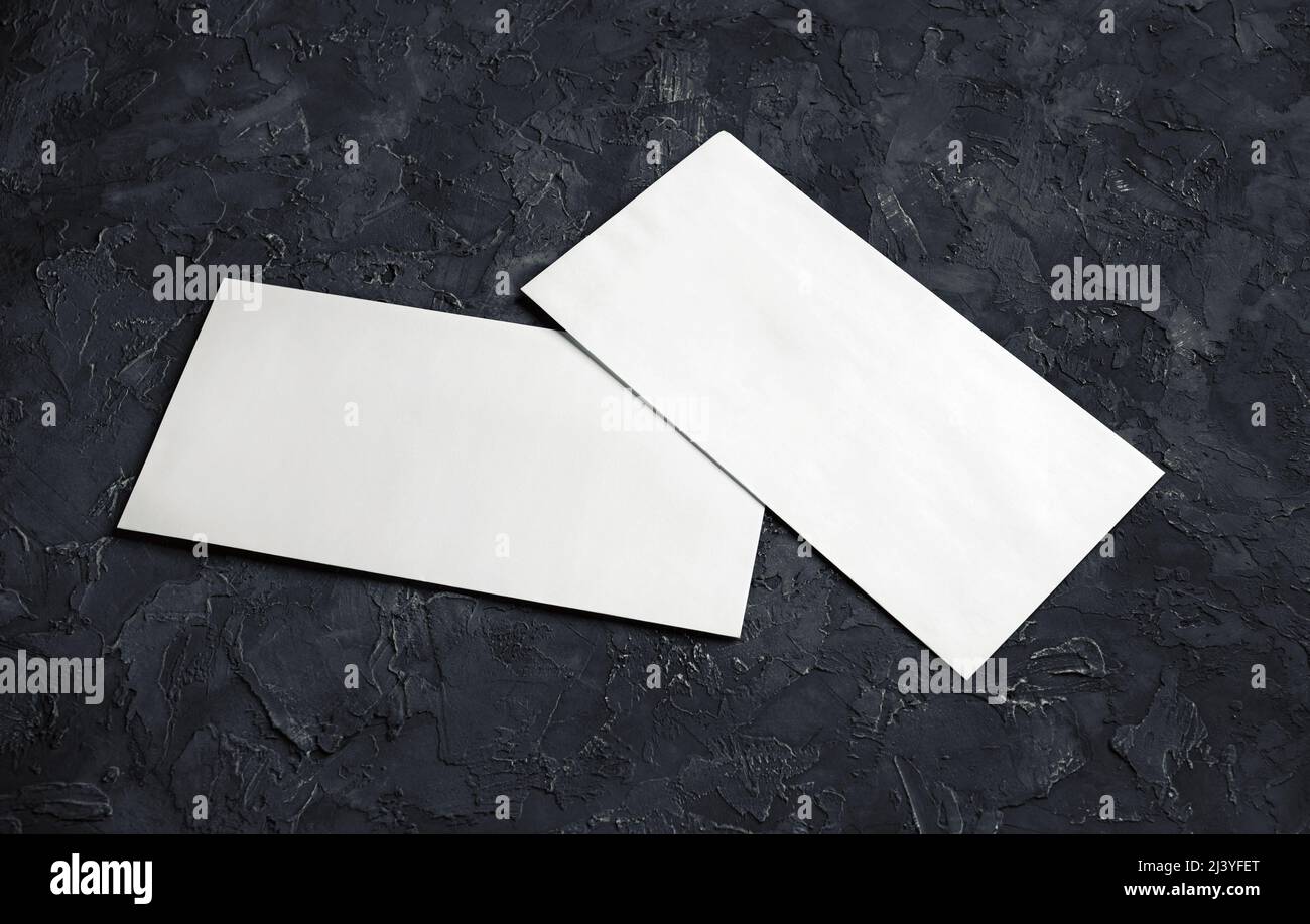 Blank white paper envelopes on black plaster background. Template for