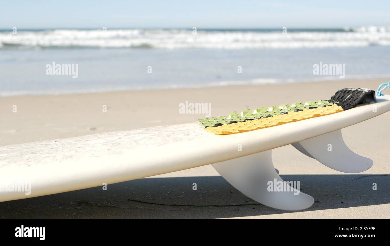 Surfboard for surfing lying on beach sand, California coast, USA. Ocean