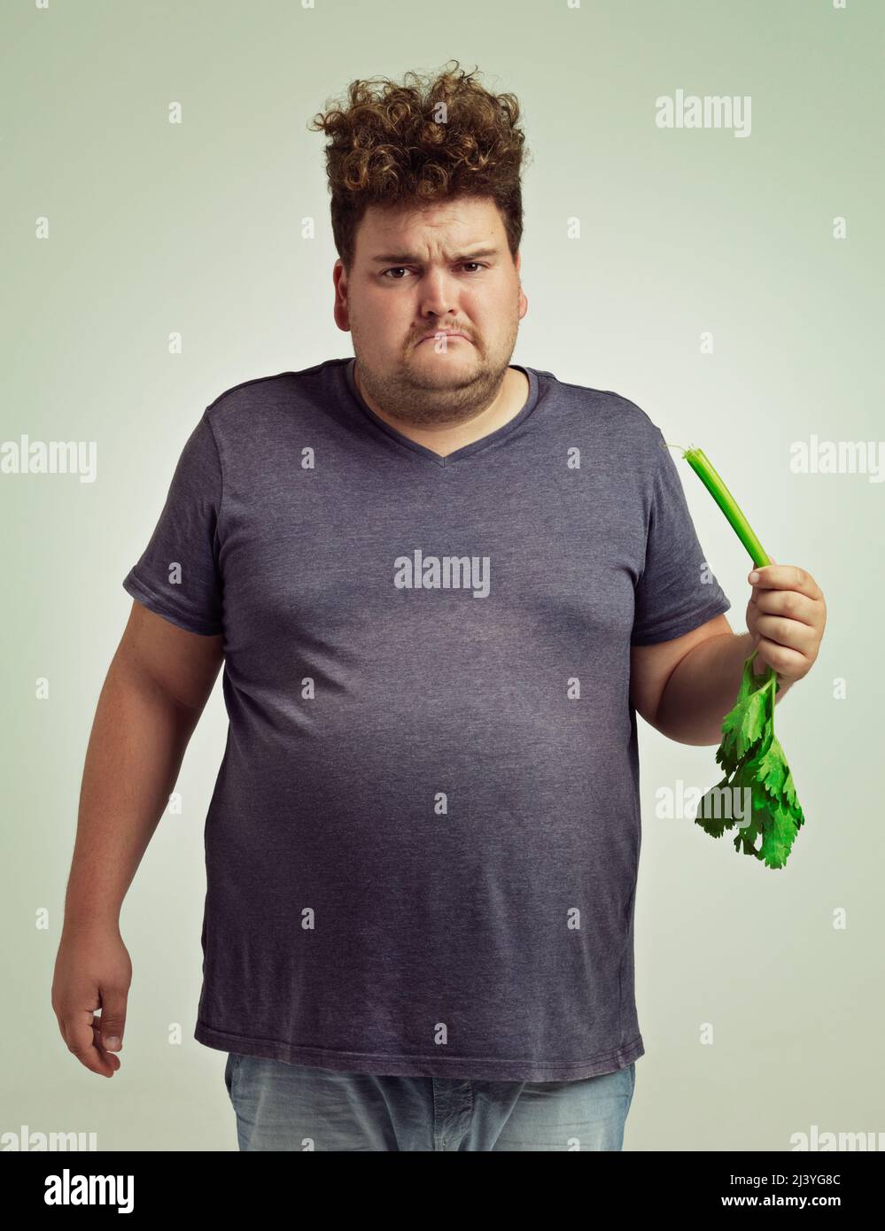 Nope, dont want it. Shot of an unhappy overweight man holding a celery stick. Stock Photo