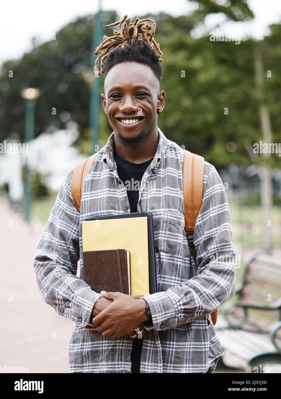 Hard work pays off. Shot of a young man holding books on campus Stock