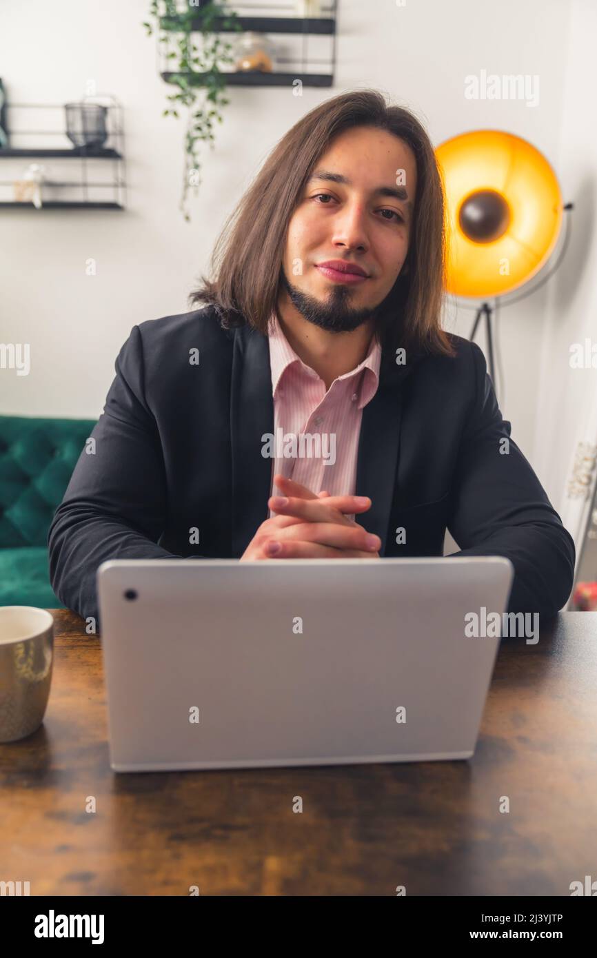 Young smiling dark-haired man sitting by the table and laptop remote job concept . High quality photo Stock Photo