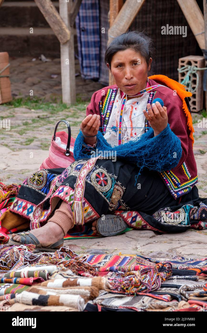 Quechua woman wearing traditional Andes clothing weaving at Pisac town Sunday Market, Sacred Valley, Peru. Stock Photo