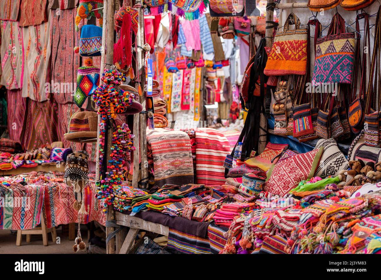 Andean textiles, traditional colourful Peruvian blankets, hats and purses for sale at the Pisac public market, Peru Sacred Valley. Stock Photo