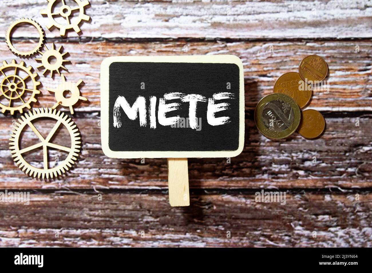 Miete in German language, white chalk type on black board, Euro money coin stacks of growth on wood table Stock Photo